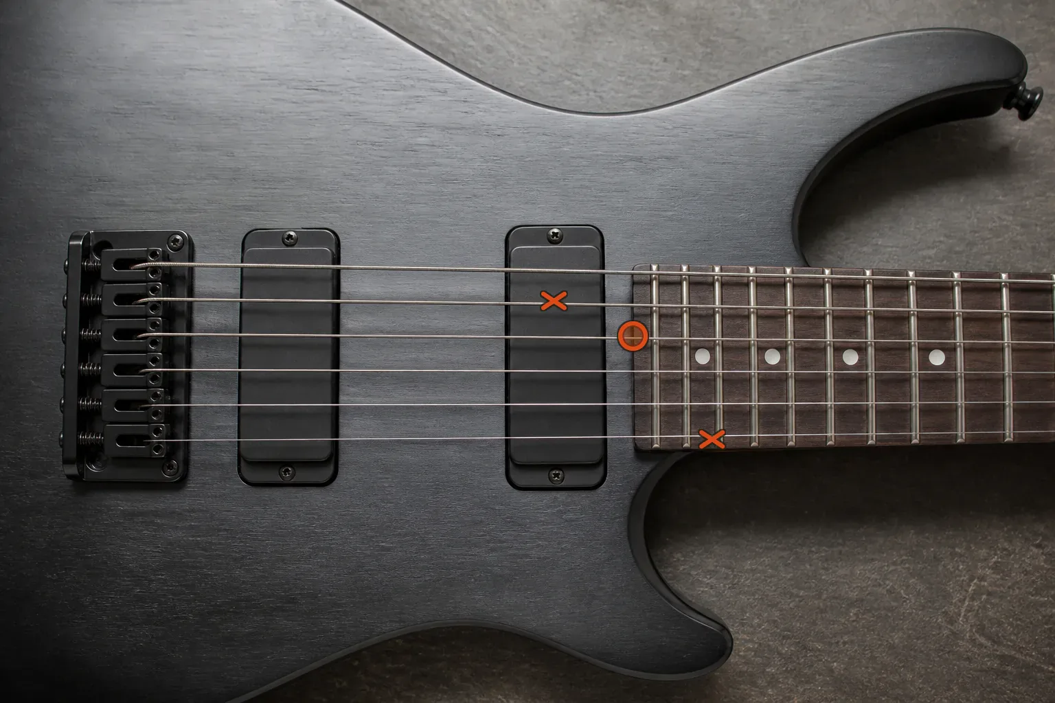 Six-string electric guitar viewed from above with an orange ring marking a target string and crosses marking neighbouring strings to check for noise