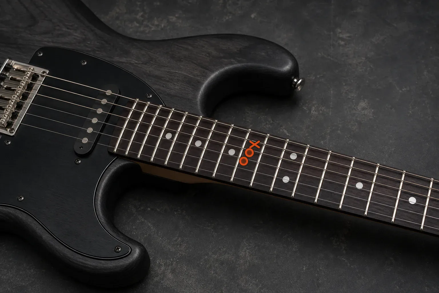 Six-string electric guitar fretboard with an orange cross and two orange circles on three neighbouring strings